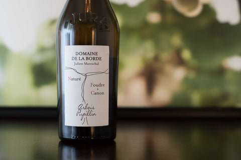 Wine bottle with a label on a blurred natural background