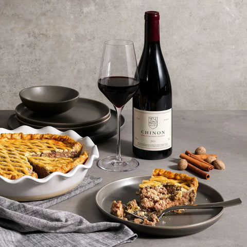 Pie with a bottle of wine and a glass on a gray surface