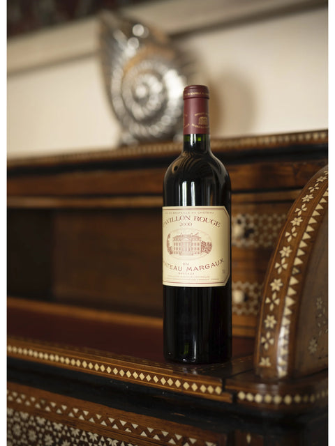 Bottle of Château Margaux wine on a wooden surface with a decorative background